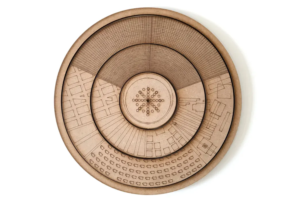 A round laser-cut MDF model of the city plan, engraved with streets and buildings